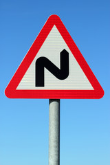 British double bend road sign and blue sky.