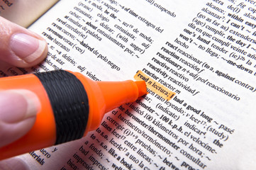 Fingers and marker on the page of Spanish dictionary