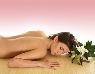 Obraz na płótnie Canvas A young naked brunette woman lying on a bamboo mat