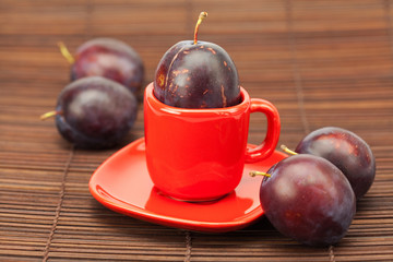 plum  in a cup and saucer on a bamboo mat