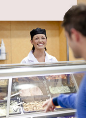 Cheerful female baker listening to a student in the queue