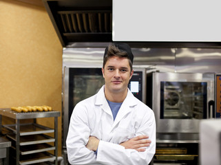 Cheerful baker standing in his kitchen waiting for baguettes
