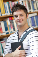 Portrait of a smart student holding a book in the library
