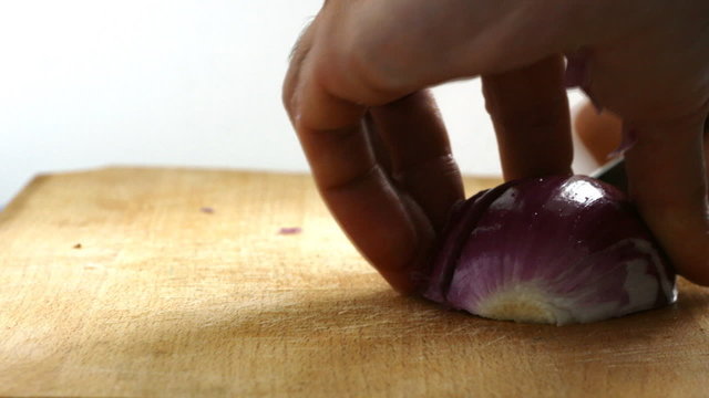 Chef hand slicing onion on a board for cooking meal