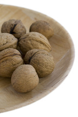 Whole walnuts in round wooden plate. isolated on white.