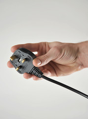 Hand holding UK 3 pin plug