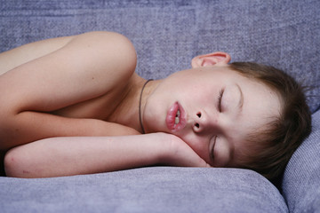 The boy sleeps on a sofa