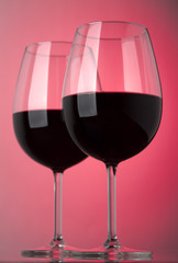 Two glasses of red wine on a pink background