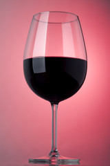 Glass of red wine on a pink background