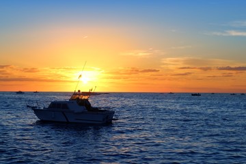 Naklejka premium Sunrise fishing boat blue sea orange sky