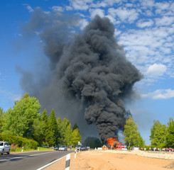 truck in fire with black smoke on the road