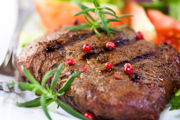 Closeup of grilled steak with rosemary and peppercorns