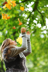 woman drop leaves in autumn park