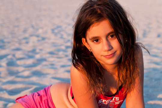 Beautiful girl with long hair lit by the sunset on a beach