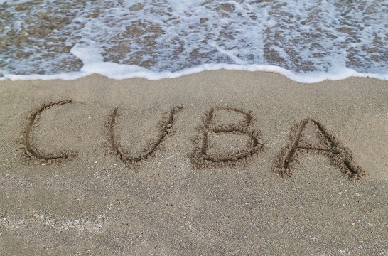 Sign reading Cuba written on a sandy beach