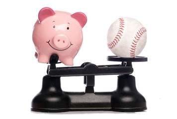 Piggybank and baseball on scales