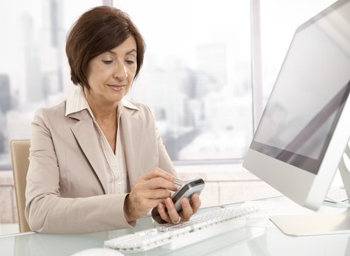 Senior professional woman using pda in office