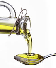 Olive oil flowing from carafe into the spoon.