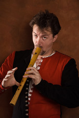 Man in a medieval suit plays a  flute © Demian