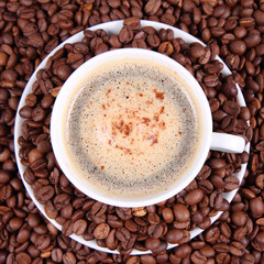 Cup of coffee with cinnamon with coffee beans around it