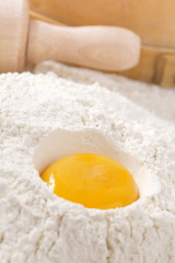 Fototapeta na wymiar egg yolk in flour, rolling pin ang sieve on background