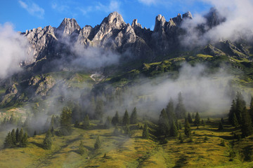 Rocky peaks above green alpine meadows in morning light