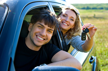 Happy couple in new car showing the keys