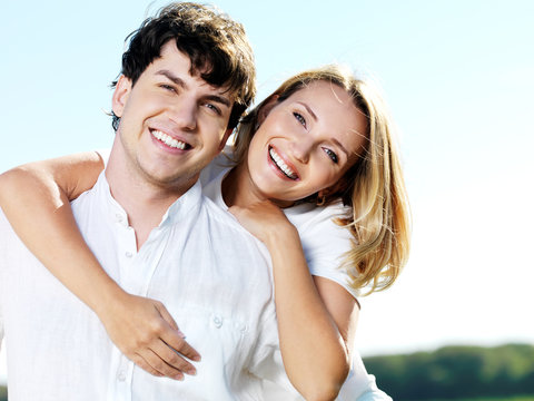 beautiful young smiling couple on blue sky background
