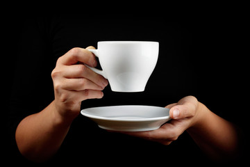 Cup of coffee in the women's hand on black background