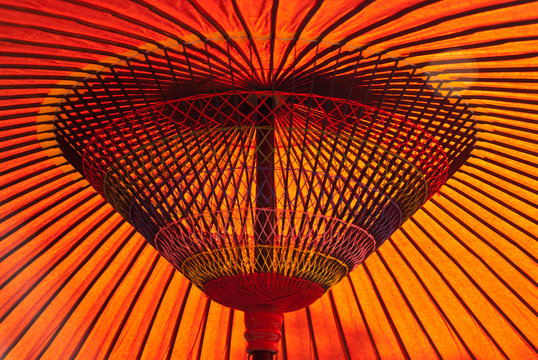 Closeup of a red, Japanese parasol with sun shining down
