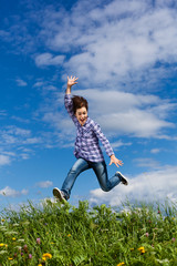 Girl jumping, running against blue sky