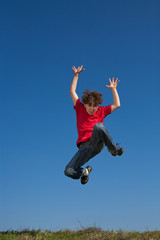 Boy jumping, running against blue sky