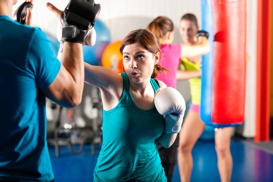 Female kick boxer with trainer in sparring