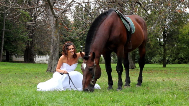 Beautiful bride and a horse walking in the park