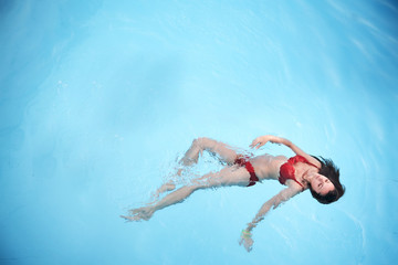 Cute brunette relaxing in a swimming pool