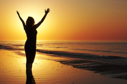 Woman with open arms at the sunset