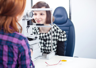 optometry concept - pretty young woman having her eyes examined