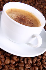 Cup of coffee surrounded by coffee beans