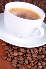 Fototapeta premium Cup of coffee with cinnamon and coffee beans on a wooden table