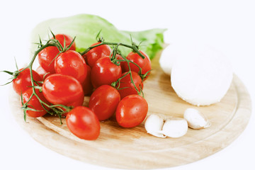 mozzarella, tomatoes, garlic and salad leaf on wooden board