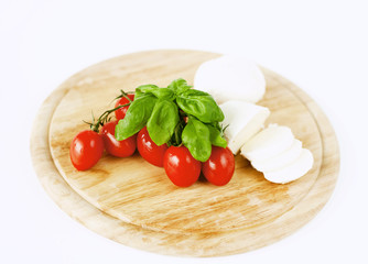 mozzarella, tomatoes and basil on wooden board
