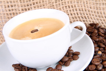 Cup of coffee and coffee beans on burlap material