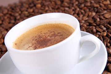 Cup of coffee with cinnamon with coffee beans around it