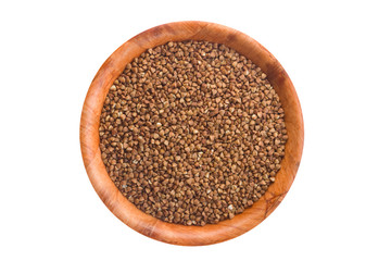 Buckwheat in round wooden plate. Isolated on white.