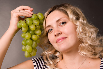 Portrait of beautiful young woman with the cluster of green vine