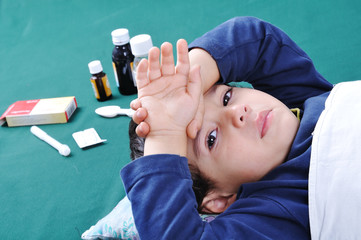 Sick child with medics and pills behind him