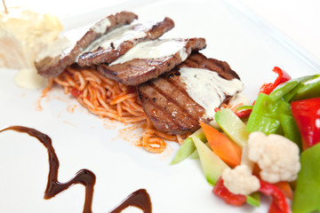 Beef steaks garnished with salad  and sauce