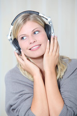 Beautiful blond woman at home with headphones on