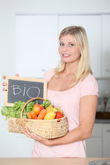 Smiling woman holding basket of organic food