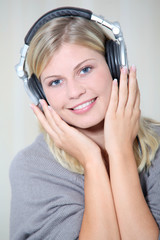 Beautiful blond woman at home with headphones on